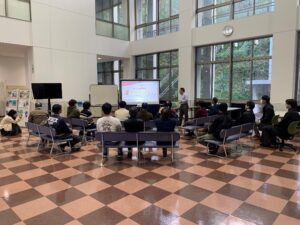 谷口教授のプレゼンテーション。会場は工学部棟玄関ホールです。